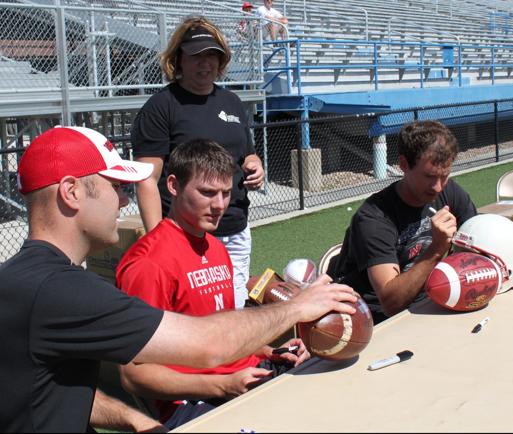 Kyle Larson, Brett Maher and Alex Henery sign autographs on footballs during the 2011 Kicker's Kick-Off